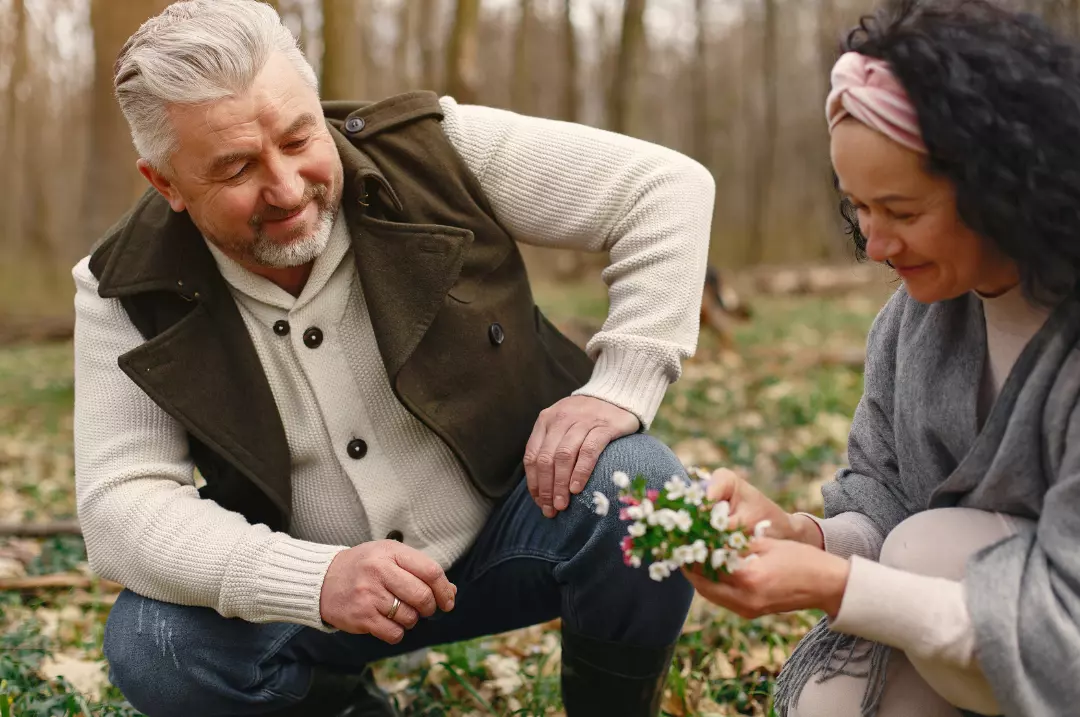Elderly couple in love with a flower in the forest.
