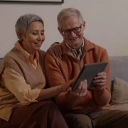 Elderly couple sitting together on sofa while consulting with their retirement financial adviser.